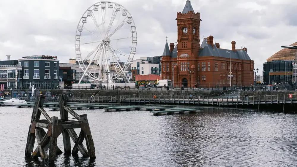 Cardiff Bay waterfront with the Pierhead Building and a ferris wheel under an overcast sky