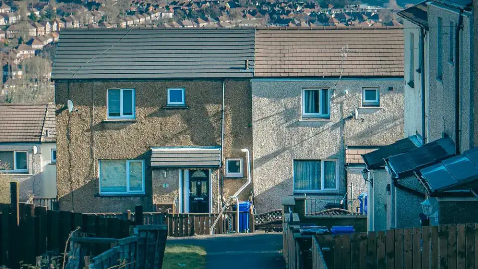 Houses on a hillside street in the South Wales valleys, with the terraced streets of a nearby town visible in the background